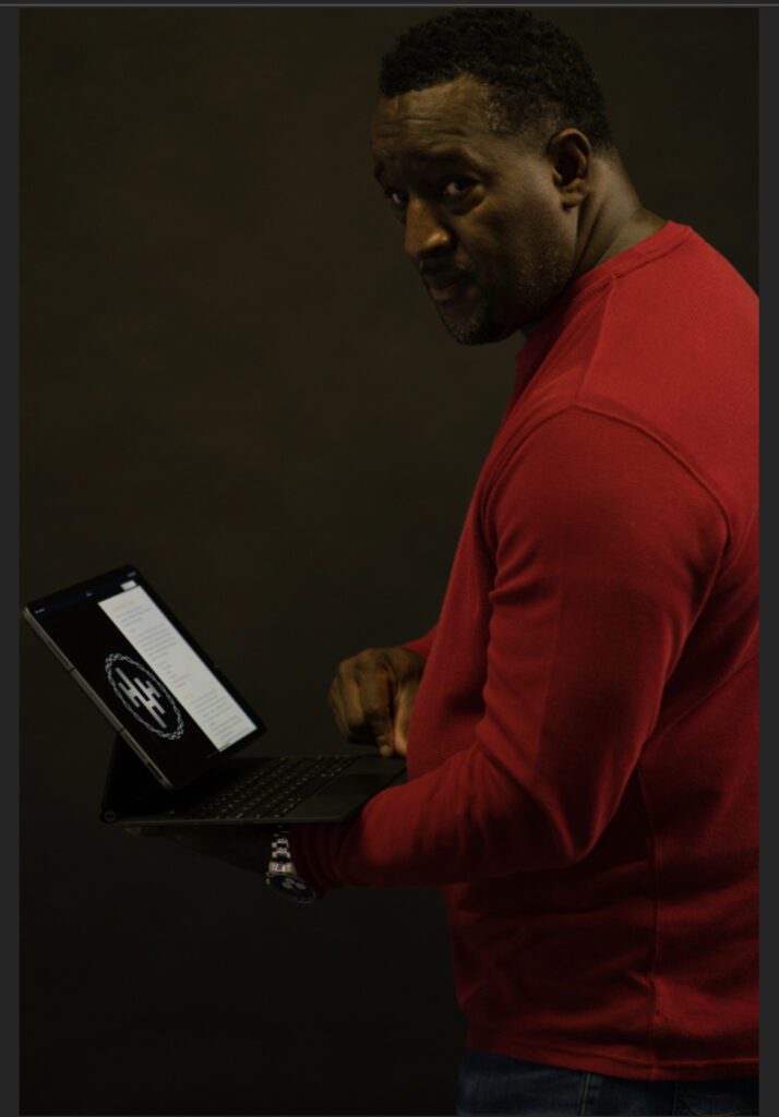 A man in red shirt holding a laptop.